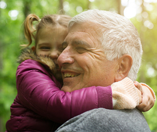 Grandfather smiling while carrying his grand daughter and hugging