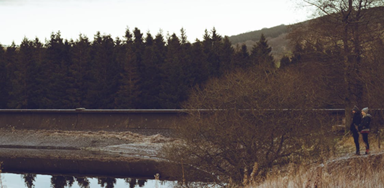 Two people standing near lake