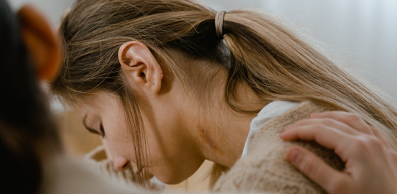 Woman crying with a hand on her shoulder
