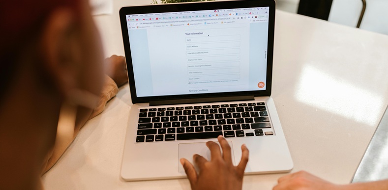 Close-Up Shot of a Person Filling out a Form Using a Laptop